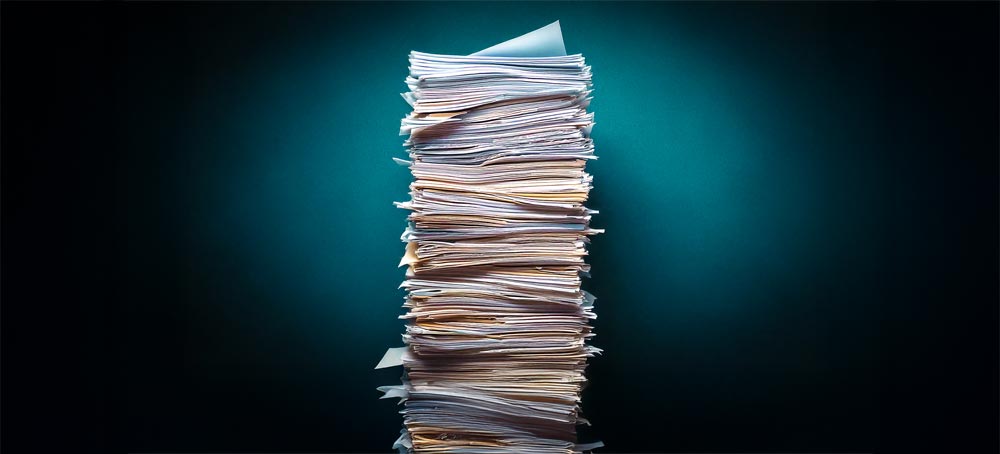 Ein Stapel Papier, der manuelles Dokumentenmanagement symbolisiert.